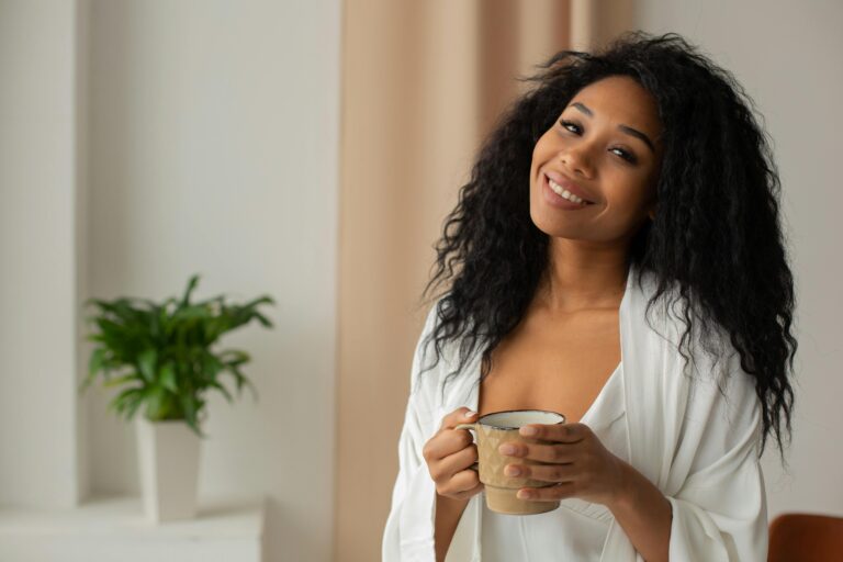 Relaxed woman in cozy home setting, enjoying a warm drink with a smile.